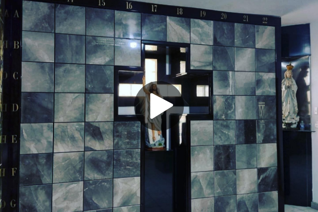 Mural de nichos en tonos grises con un diseño en forma de cruz, donde destaca una imagen de Jesús en el centro, creando un espacio de reflexión y fe