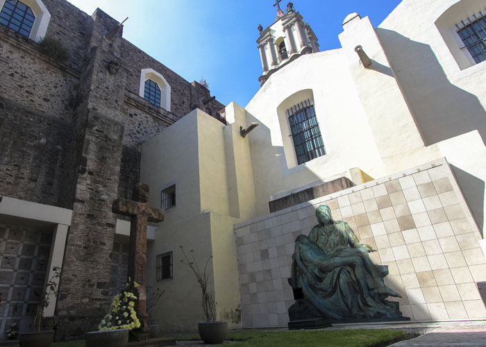 Criptas Fachada de una iglesia con escultura religiosa y cruz en el exterior