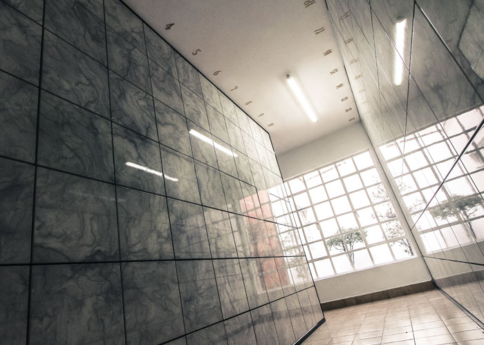 Criptas Paredes revestidas con azulejos de acabado marmoleado en un pasillo bien iluminado, resaltadas con numeración en la parte superior y una ventana que permite el ingreso de luz natural.