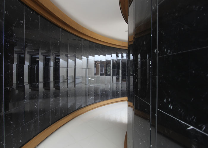 Criptas Pasillo interior curvo con revestimiento de mármol negro y detalles de madera