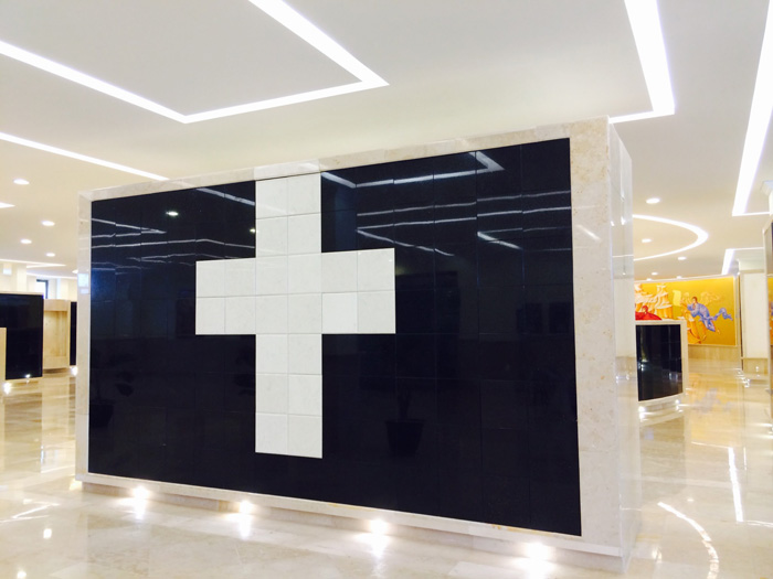 Criptas Pared de nichos en mármol negro con una cruz blanca en el centro.