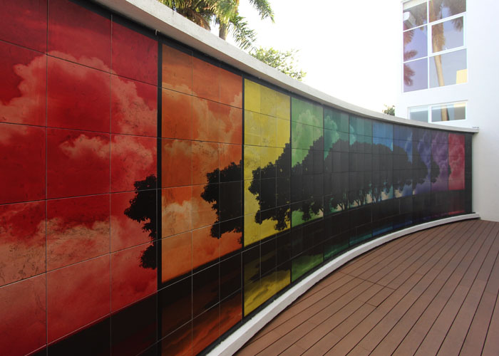 Criptas Pared exterior curva con mural colorido de nubes y silueta de árboles