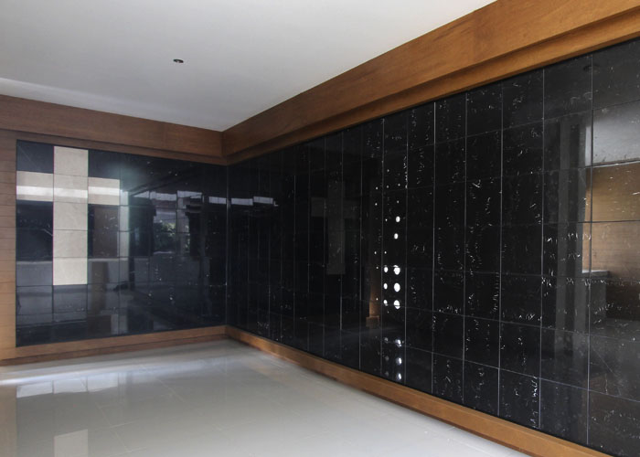 Criptas Interior con pared de mármol negro y detalles de madera, con diseño de cruz visible en la esquina