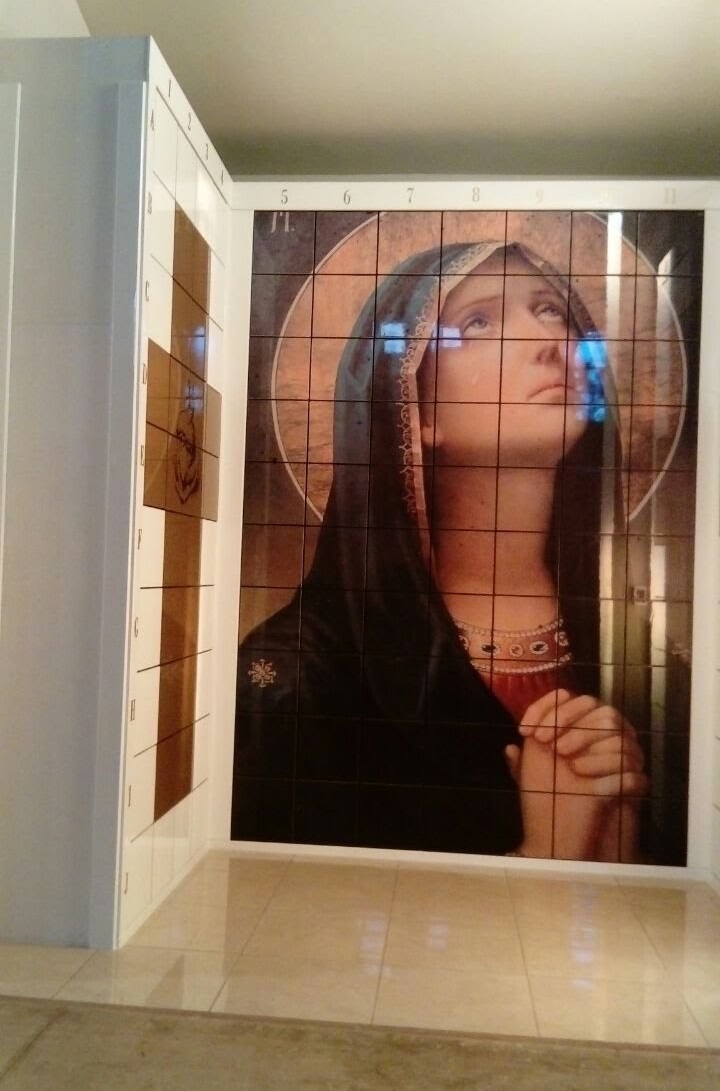 Criptas Nichos con una imagen de la Virgen María en posición de oración, con mirada hacia el cielo y rodeada de un halo, en tonos suaves y cálidos