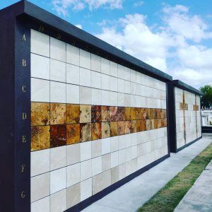 Pared de nichos en tonos claros y oscuros formando una cruz central