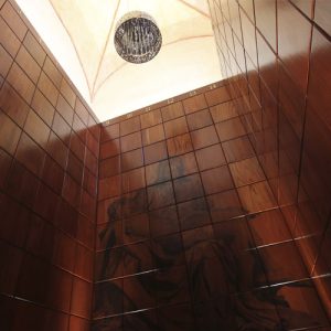 Espacio interior con revestimiento de madera y arte religioso grabado en la pared